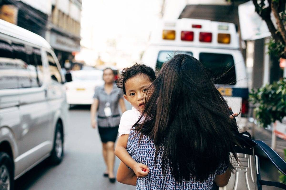 Woman holding a child on a road.