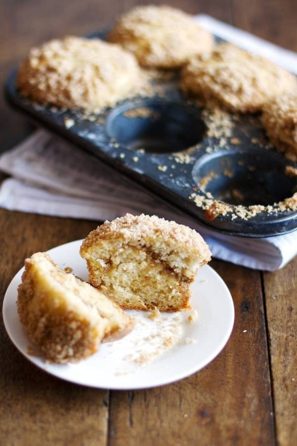 Coffee cake muffin on a white plate near a muffin tin.