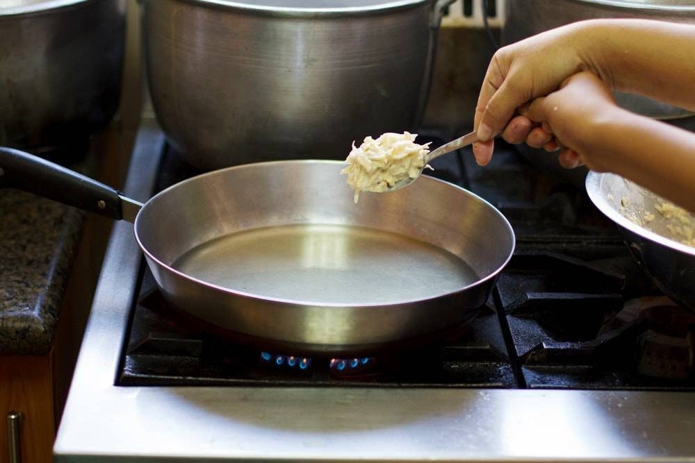 Camotes on a spoon over a pan.