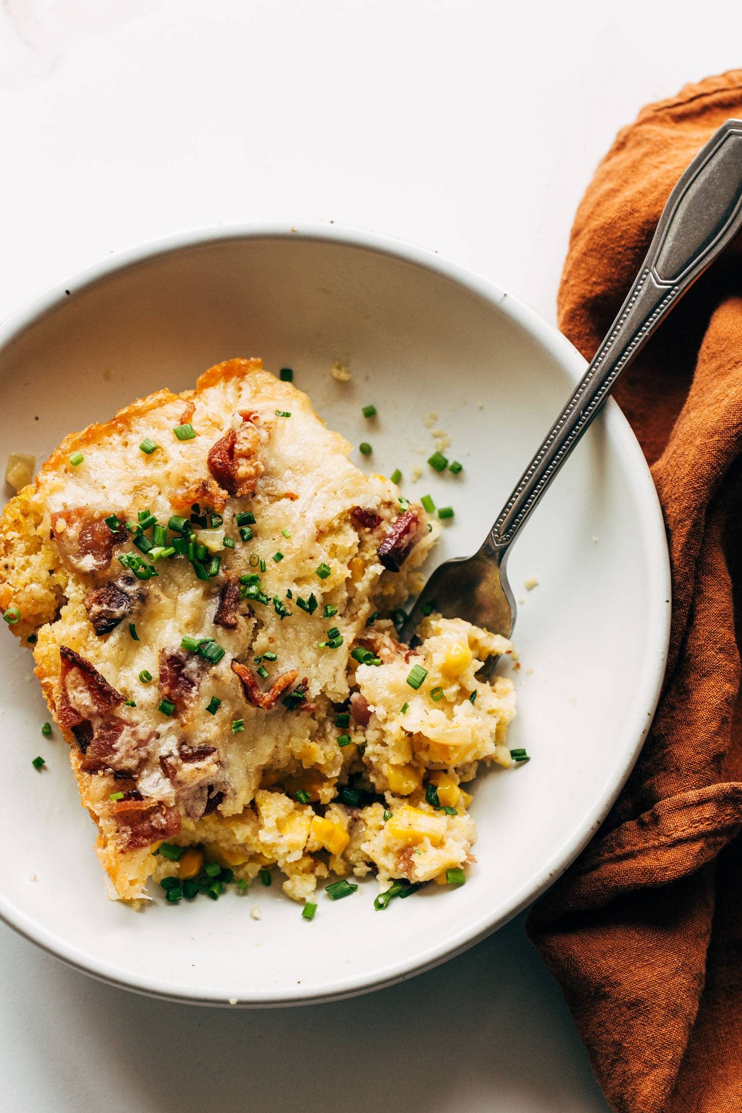Corn casserole on a plate with a fork.