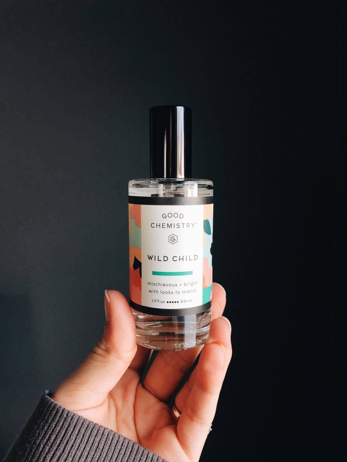 A hand holding a bottle of perfume name "Good chemistry wild child".
