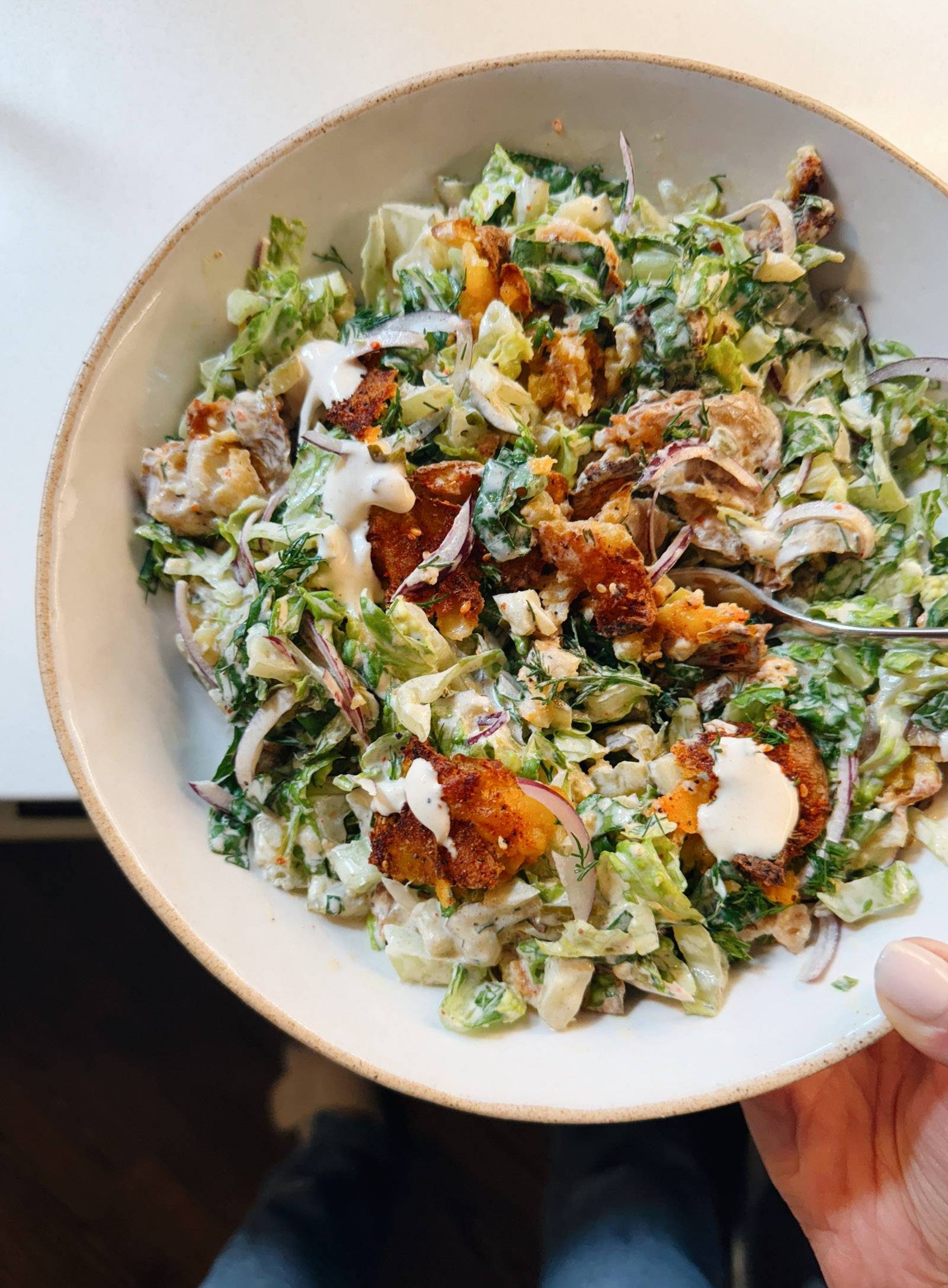 Crispy smashed potatoes in a bowl with salad.