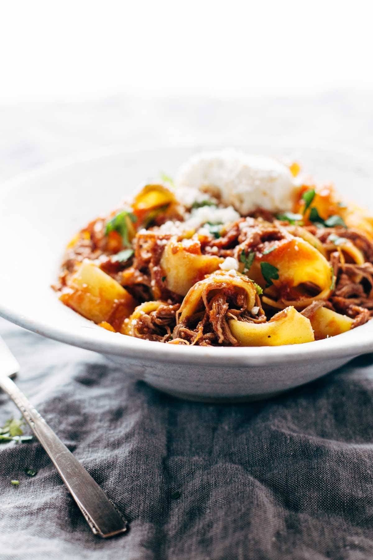 Beef ragu with pappardelle in a bowl with cheese.