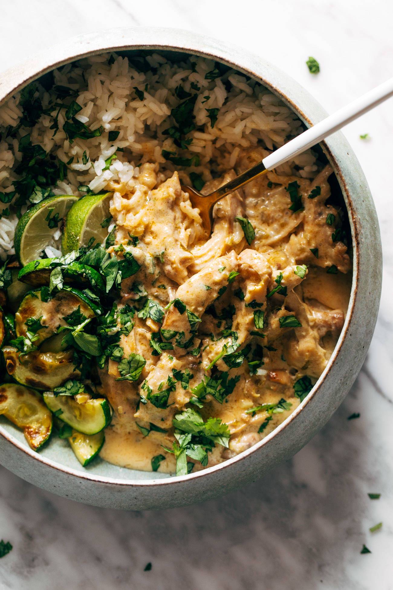 Lemongrass chicken with rice and zucchini in a bowl with fresh herbs.