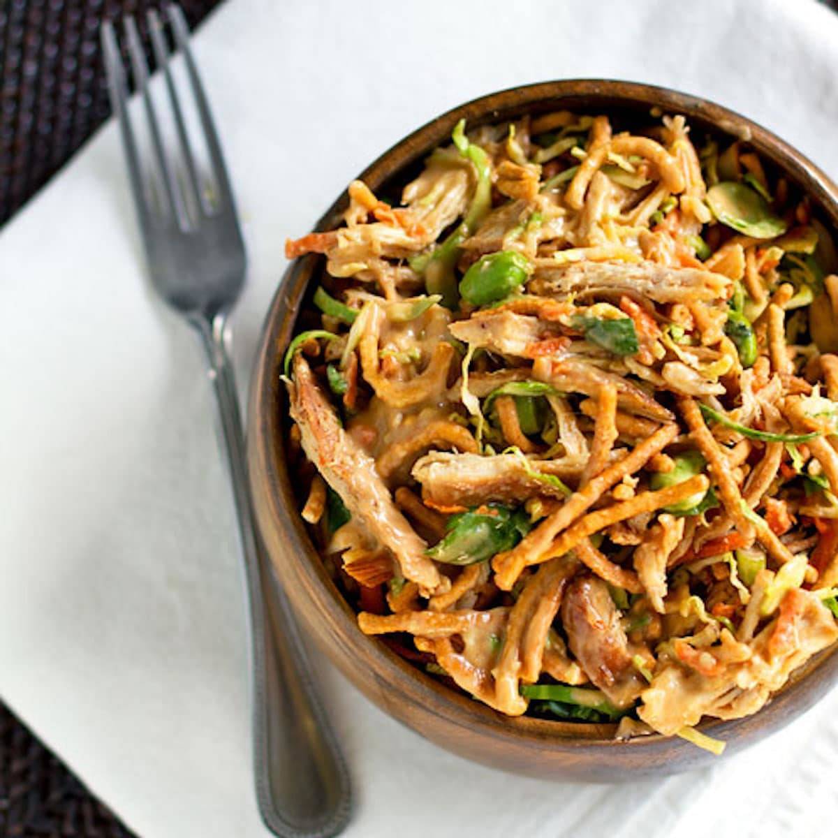 Asian chicken salad in a wooden bowl with a fork.